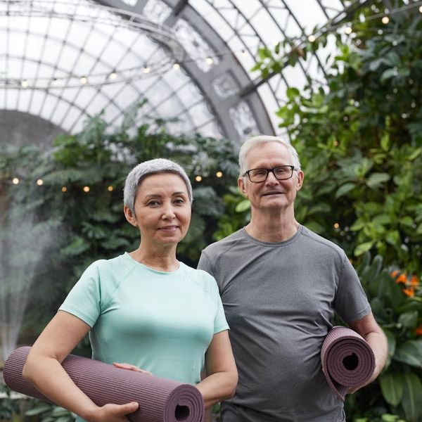 Diverse group of women smiling and holding yoga mats.